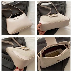 Detail view of beige crossbody bag with gold bow buckle and textured leather stitching