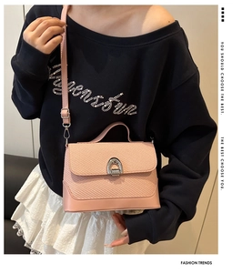Détail du sac selle en cuir tressé rose avec boucle fer à cheval argentée et sangle