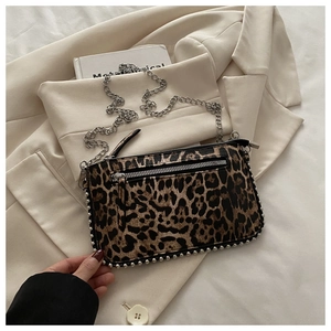 Detail van de crossbodytas met luipaardprint en zilveren studs op beige blazer