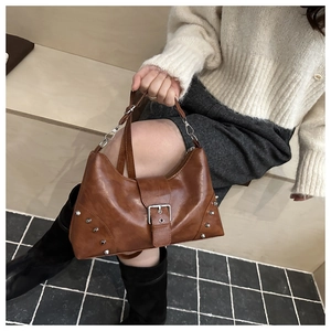 Detailed close-up of brown vintage hobo bag with silver studs and polished faux leather