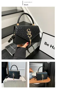 Detail of black crossbody bag featuring woven flap, gold SS logo, and metal tassels