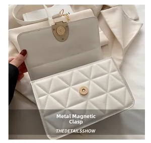 Detail shot of the gold magnetic hardware buckle on a white quilted chain crossbody bag