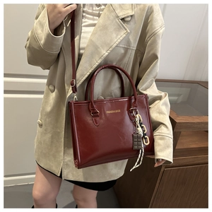 Détail d'un sac à main bordeaux en cuir verni avec breloque chocolat et texte doré