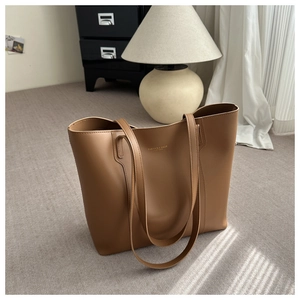 Detail view of large brown leather tote bag with gold lettering on grey carpet
