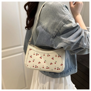 Close-up of white underarm bag featuring red cherry prints and stylish chain strap