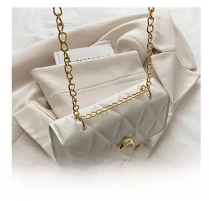 Close-up of white quilted leather crossbody bag with gold chain and metal buckle