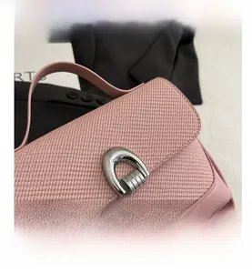 Gros plan sur la texture tissée rose et le cuir du sac avec boucle fer à cheval
