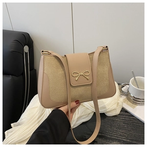 Detail of beige crossbody bag featuring sparkling glitter panel and gold bow decoration