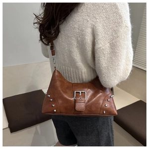 Detailed view of brown retro shoulder bag with silver studs and a large buckle on soft leather