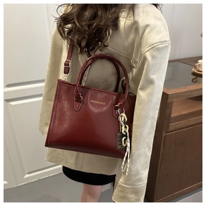 Vue détaillée du sac à main en cuir bordeaux avec lettrage doré et bijou de sac
