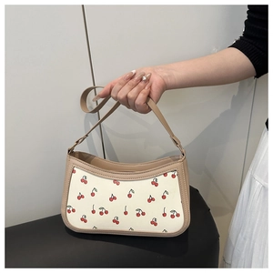 Detail of crescent shoulder bag featuring red cherry prints and beige synthetic leather