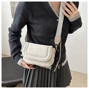 Detail of beige saddle crossbody bag with suede finish and adjustable wide strap