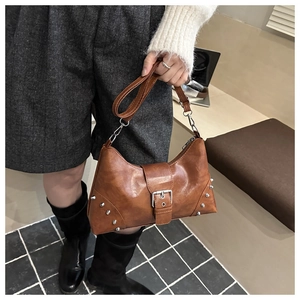 Detailed side view of caramel crescent hobo bag with silver studs and buckle strap