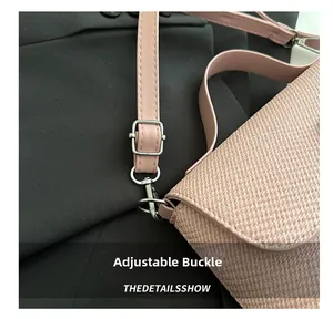 Détail de la boucle métallique argentée réglable sur un sac bandoulière tissé rose