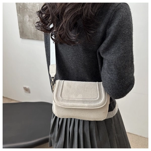 Beige suede-style crossbody bag detail with triple-stitched flap and patterned strap