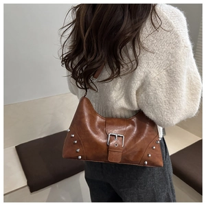 Detail view of a vintage brown leather shoulder bag with silver studs and a large buckle