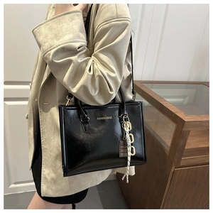 Sac à main chic en cuir verni noir avec texte doré et détail de foulard en soie