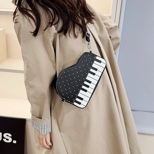 Unique piano-shaped crossbody bag with black and white polka dots and piano key design