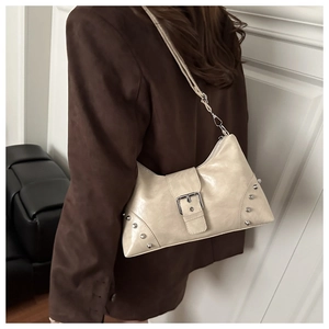 Detail view of off-white leather hobo bag with silver rivets and magnetic buckle strap