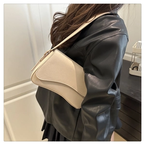 Close-up of minimalist cream leather crossbody bag featuring a curved flap design