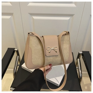 Close-up of beige leather handbag featuring a golden bow buckle and smooth texture