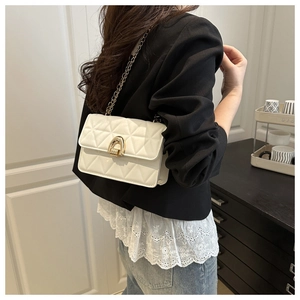 Close-up of white quilted chain shoulder bag with gold hardware worn by a model