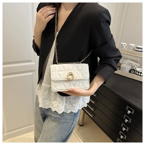 Close-up of white quilted crossbody bag with gold chain strap and horseshoe metal lock