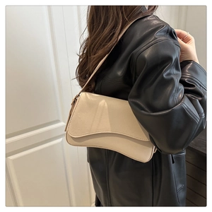 Detail of off-white leather baguette bag with curved flap shown on a model