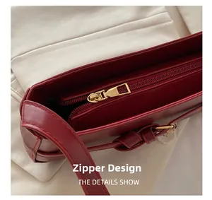Detail van de gouden ritssluiting op deze trendy rode leren onderarmtas voor dames