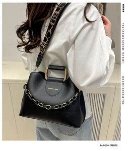 Detail of black bucket bag with gold chain and stylish geometric jacquard wide strap