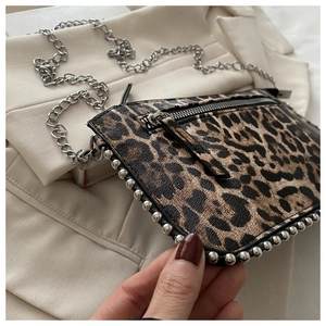 Detailweergave van luipaardprint crossbodytas met zilveren studs en een kettingriem