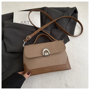 Détail du sac bandoulière rétro tissé avec garniture en cuir brun et fermoir rotatif
