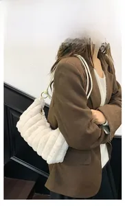 Gros plan sur un sac à bandoulière en peluche avec matelassage vertical et zip doré