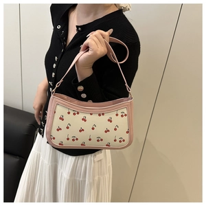 Detail of trendy cherry print underarm bag with pink trim and silver chain strap