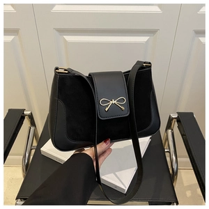 Close-up of elegant black velvet and leather shoulder bag with gold bow clasp