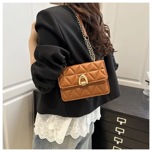 Detail of a brown quilted leather crossbody bag with a gold horseshoe lock and chain strap