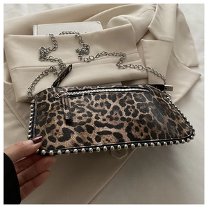 Detail van luipaardprint tas met zilveren studs en metalen ketting op beige blazer