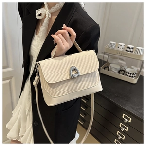 Détail de la texture tressée et boucle en métal argenté sur un sac selle couleur crème