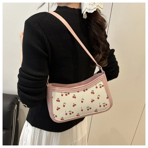 Close-up of pink cherry print shoulder bag worn by model with metallic chain strap