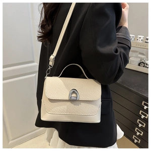 Détail du sac bandoulière blanc cassé avec texture tissée et boucle fer à cheval argent