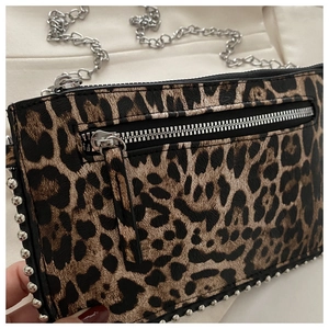 Detail van luipaardprint tas met zilveren studs en metalen kettingriem textuur