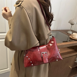 Retro red faux leather shoulder bag with silver rivets and metal buckle on trench coat