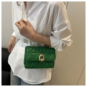 Detailed macro view of green quilted PU leather bag with golden chain and U-shaped metal lock