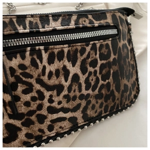 Detail van luipaardprint tas met zilveren klinknagels en metalen ketting schouderband