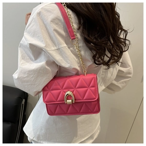 Detail of rose pink quilted chain bag showing the metallic lock and elegant shoulder strap