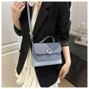 Détail du sac selle bleu clair avec texture tissée et boucle fer à cheval argentée