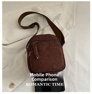 Detailed close-up of brown corduroy crossbody bag showing zipper pocket and fabric texture