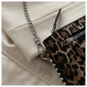 Detailopname van luipaardprint tas met zilveren ketting en metalen klinknageldetails