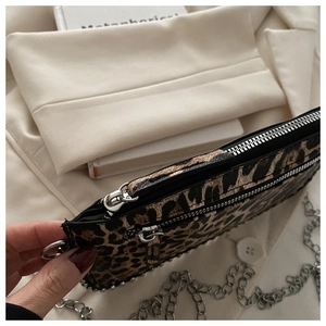 Detail van de crossbodytas met luipaardprint, zilveren studs en meerdere ritsvakken