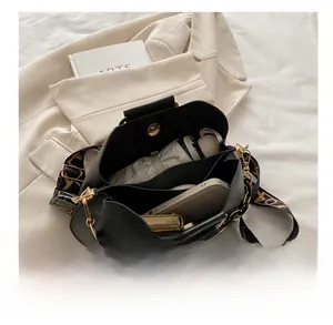 Top view of black leather bucket bag interior with compartments and wide woven strap